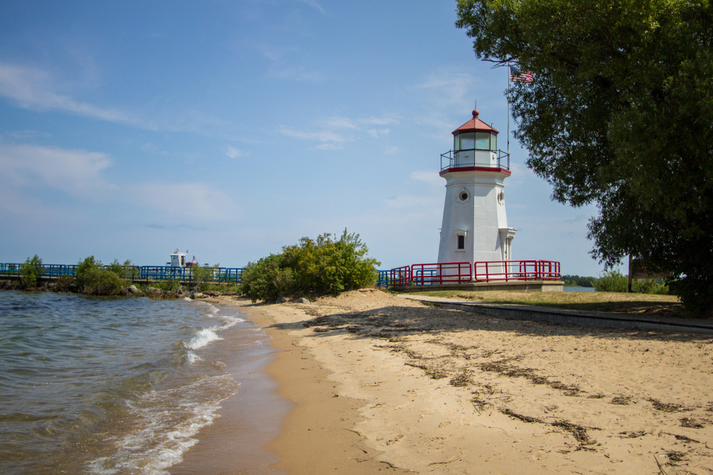 Sandy Michigan Beach in Cheboygan with white lighthouse that has red railings.