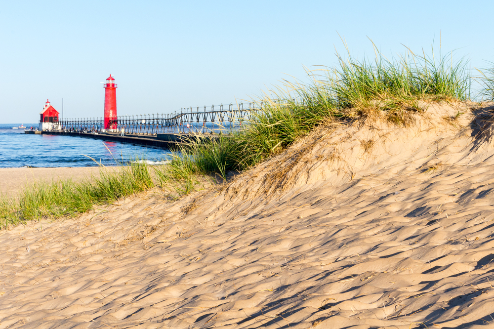 White Sandy Grand Haven Beach in Michigan  with red  lighthouse in background.