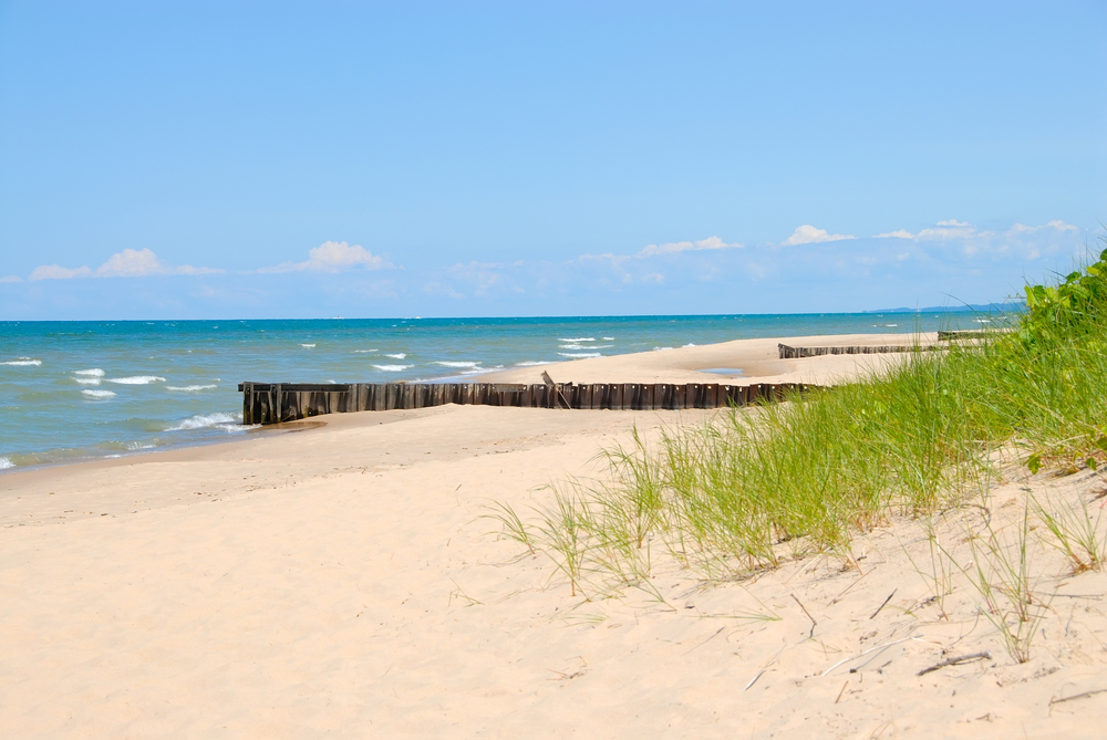 Warren Dunes is one of the best beaches in Michigan with all its white sandy dunes. Waves rolling in and blue sky in background.