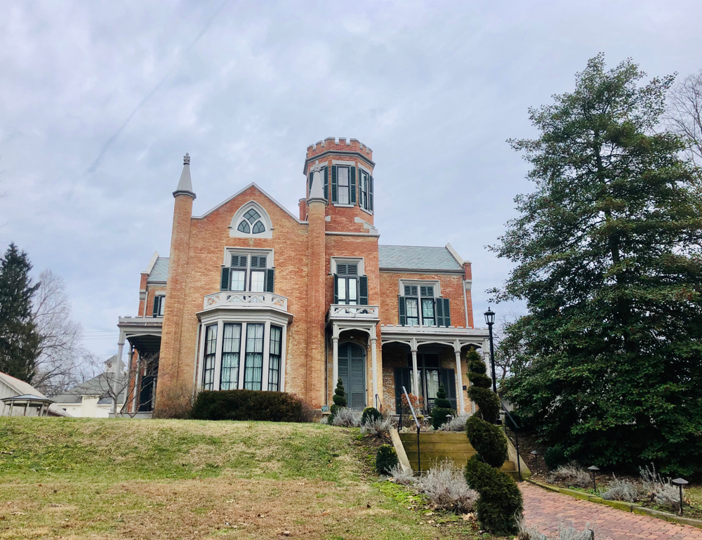 Gothic inspired orange-brick Ohio  castle with brick walkway leading to ornate front porch.