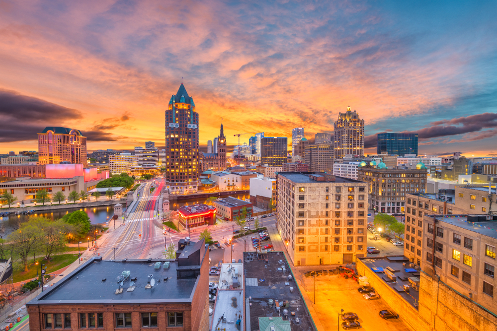 An aerial view of illuminated Milwaukee WI with sunset in background, one of the best day trips from Chicago.