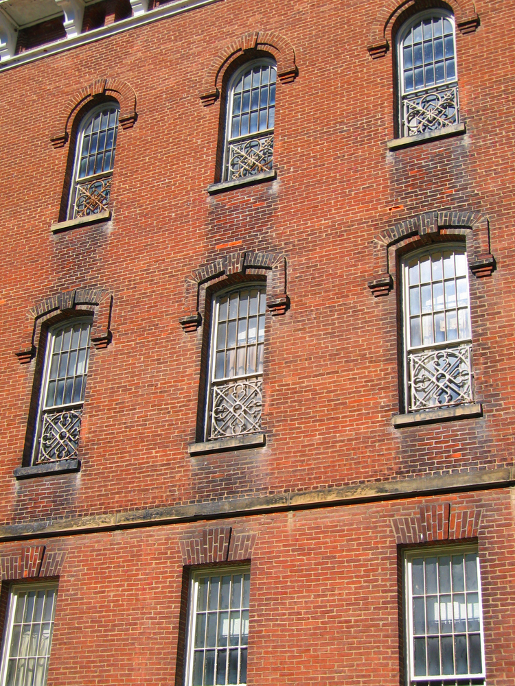 Close up photo of side old red brick building with ornate windows, an asylum Ohio haunted place that will creep you out.