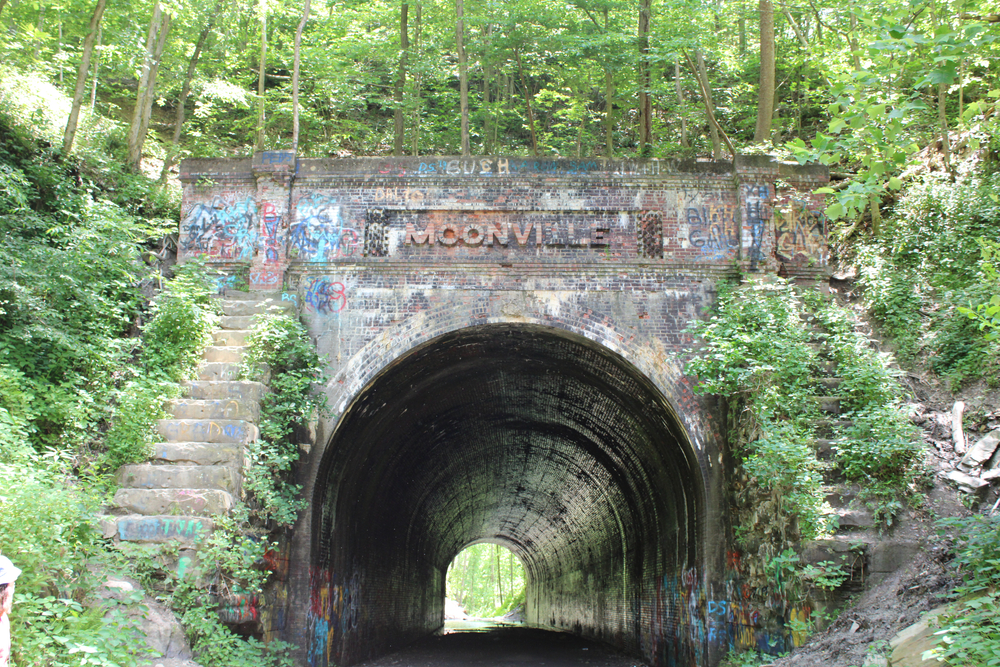 Creepy Moonville tunnel with overgrown trees and steps on either side of the stone archway. One of the haunted places in Ohio.