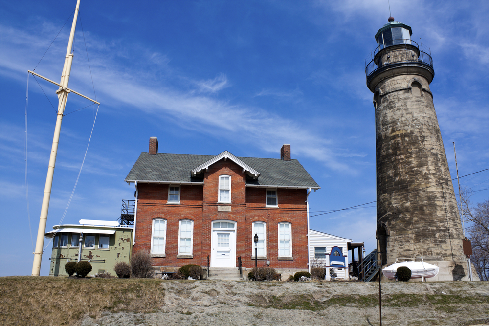 Photo of red brick building with stone lighthouse. A feline presence is felt at the Old Fairport Lighthouse one of the haunted places in Ohio.