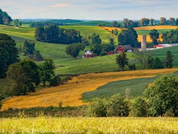 Photo of rural roaming hillsides with red barn with silo.