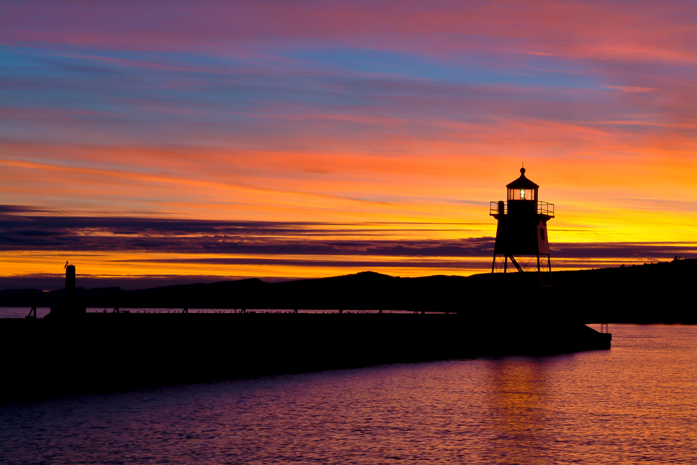 Lighthouse of small town in Minnesota with gorgeous orange/yellow sunset filling sky.