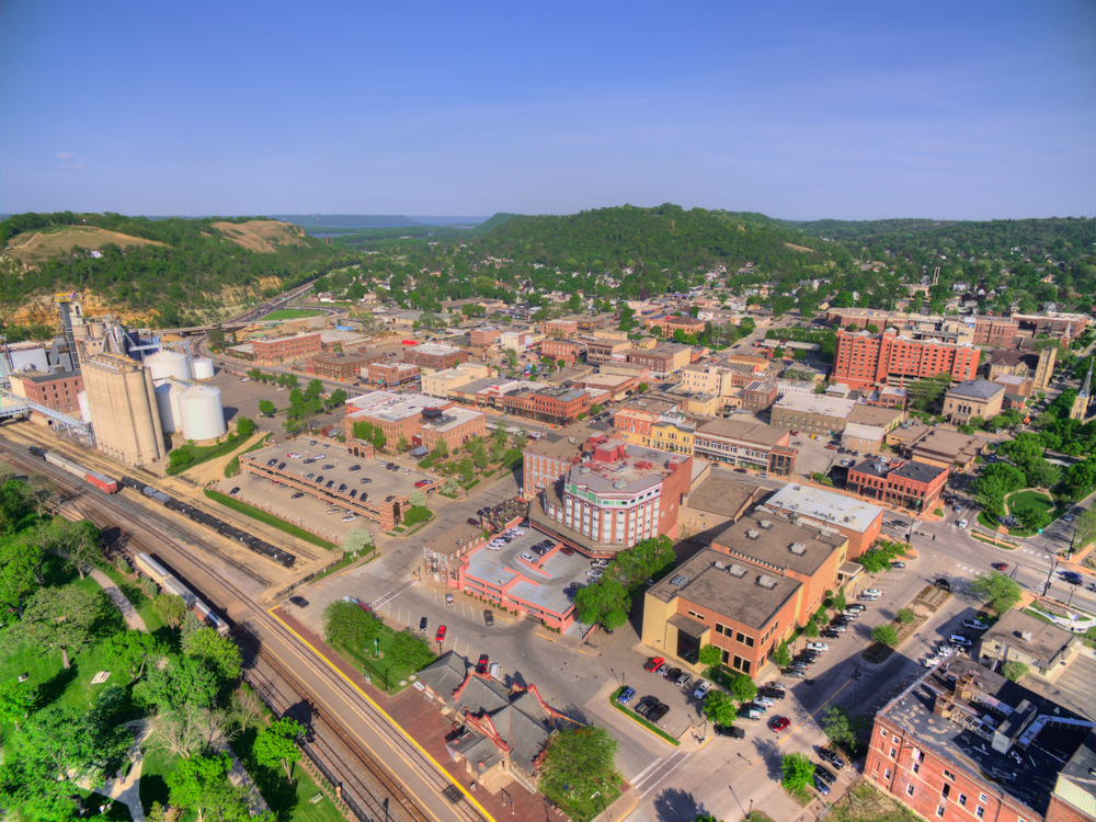 Aerial view of small town with vintage  red brick buildings and rolling hills in background.