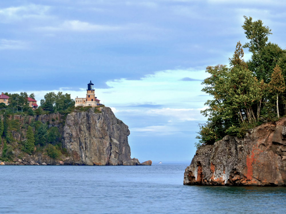 The Split Rock Lighthouse in Two Harbors Minnesota high up on stone cliff with blue waters below.