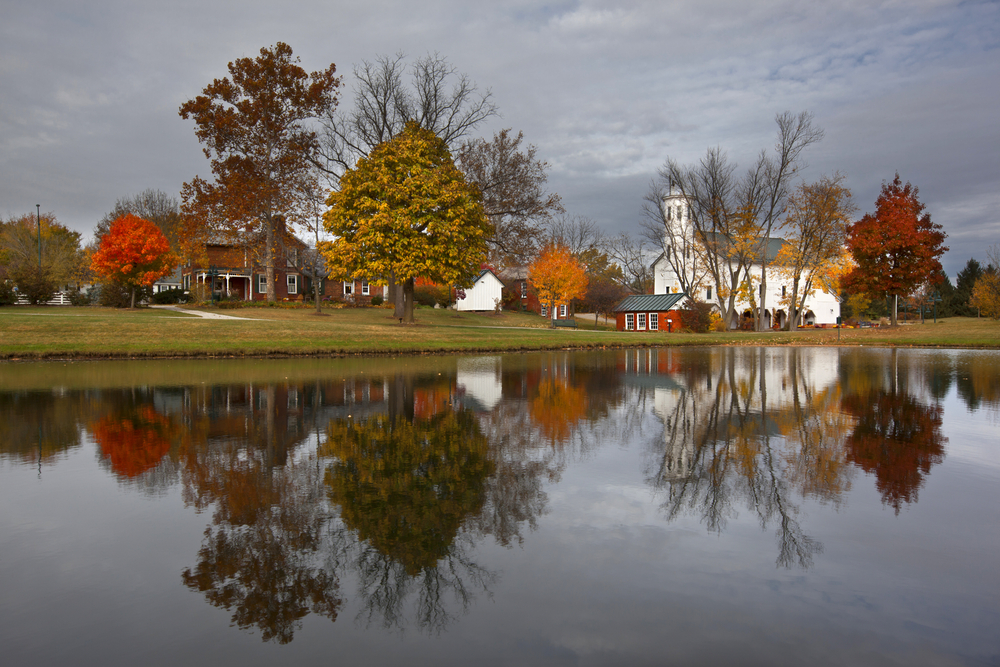 Lovely red-bricked house and white church with steeple sitting on lake in Westerville, small town in Ohio.