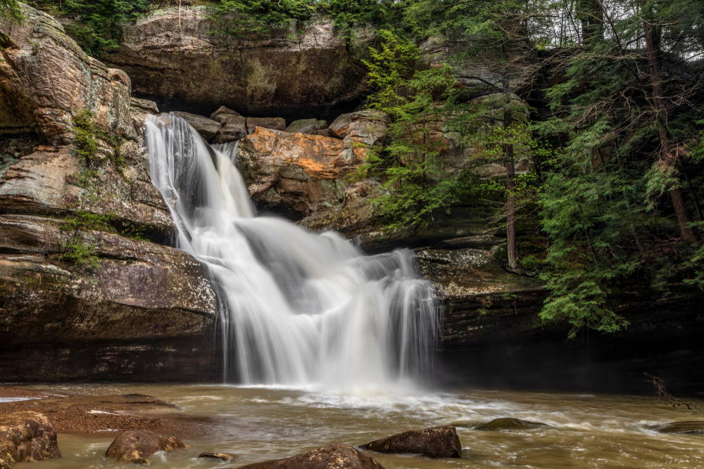 Waterfalls spilling down through rock ledges to water below.