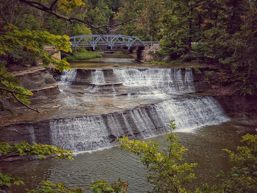 Paine waterfalls in Ohio are easy to get to - a series of cascading falls along two distinct sections with blue bridge in background.