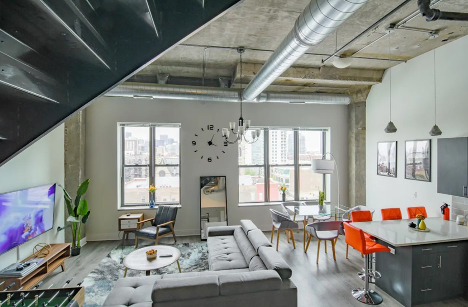 The interior of a loft penthouse in chicago that is painted white and has large windows that look out onto the city skyline