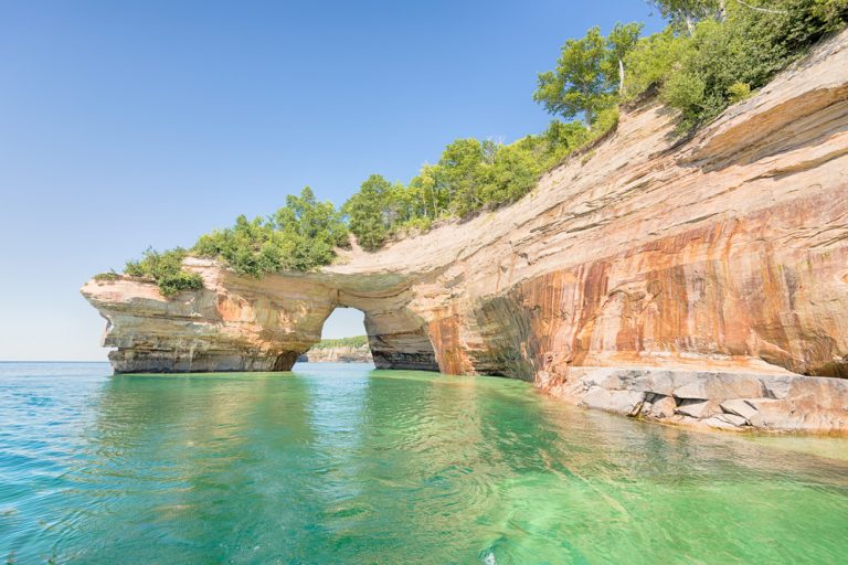 Stone arch and brilliant green waters at Pictured Rocks Midwest national park.