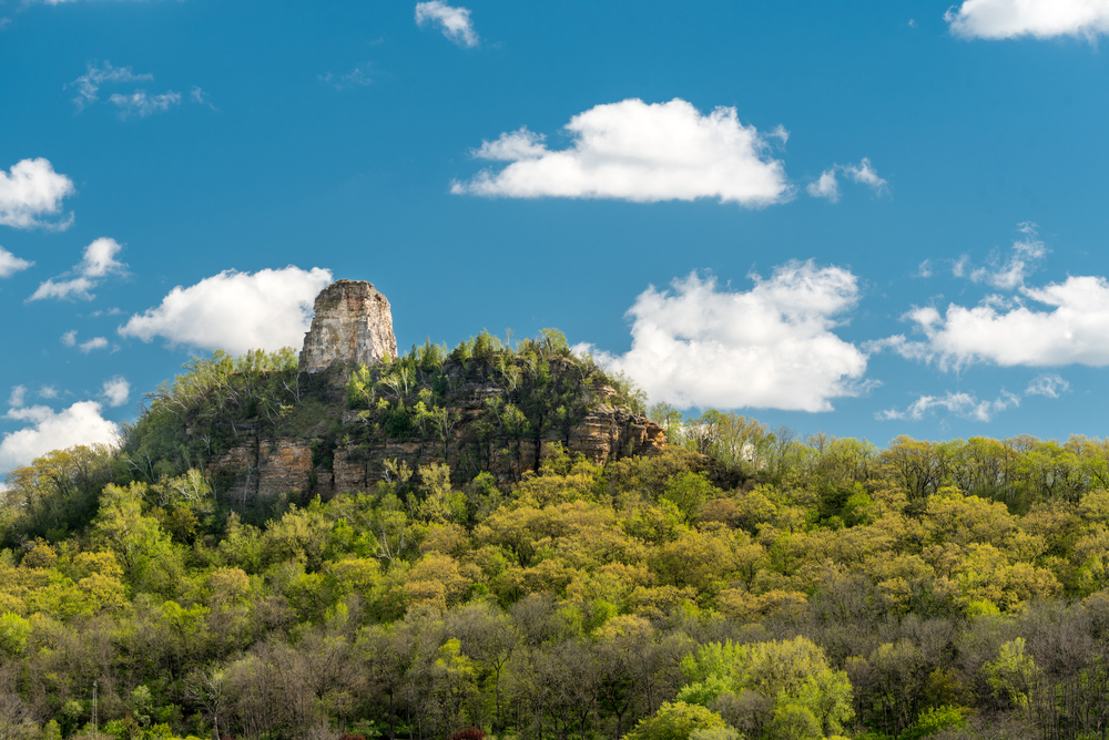 One of the bluffs in Winona Minnesota covered in trees on a sunny day one of the best romantic Midwest getaways