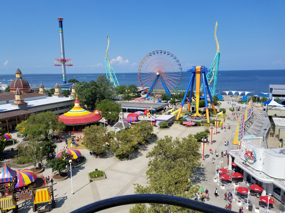 A high view of an amusements park in the midwest with a ferris wheel and the ocean in the background