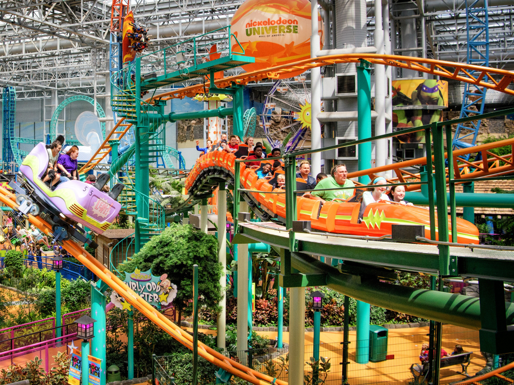 A blue and orange roller coaster with people riding in an amusement park in the Midwest