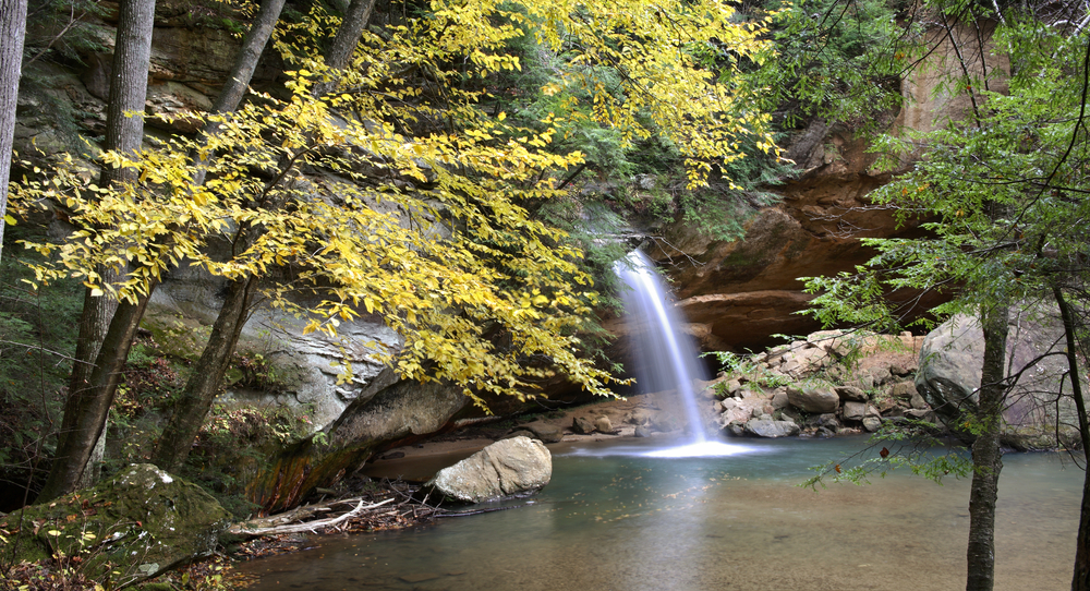 Ohio waterfall in autumn with trees with yellow leaves in foreground.