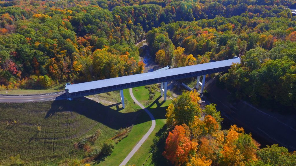 Drone shot of covered bridge with beautiful autumn trees in surrounding countryside.