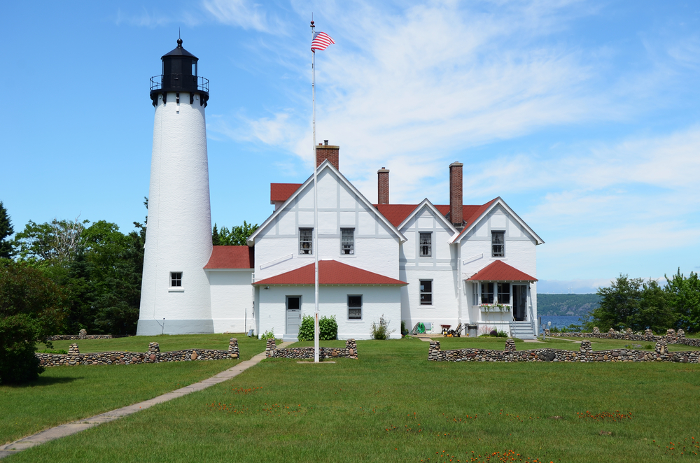 The front of a large white lighthouse with red trim on the shores of Lake Superior coolest lighthouses in Michigan