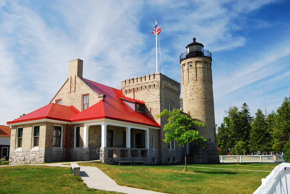 A large brown stone lighthouse that resembles a castle with a square turret and a red roof lighthouses in Michigan