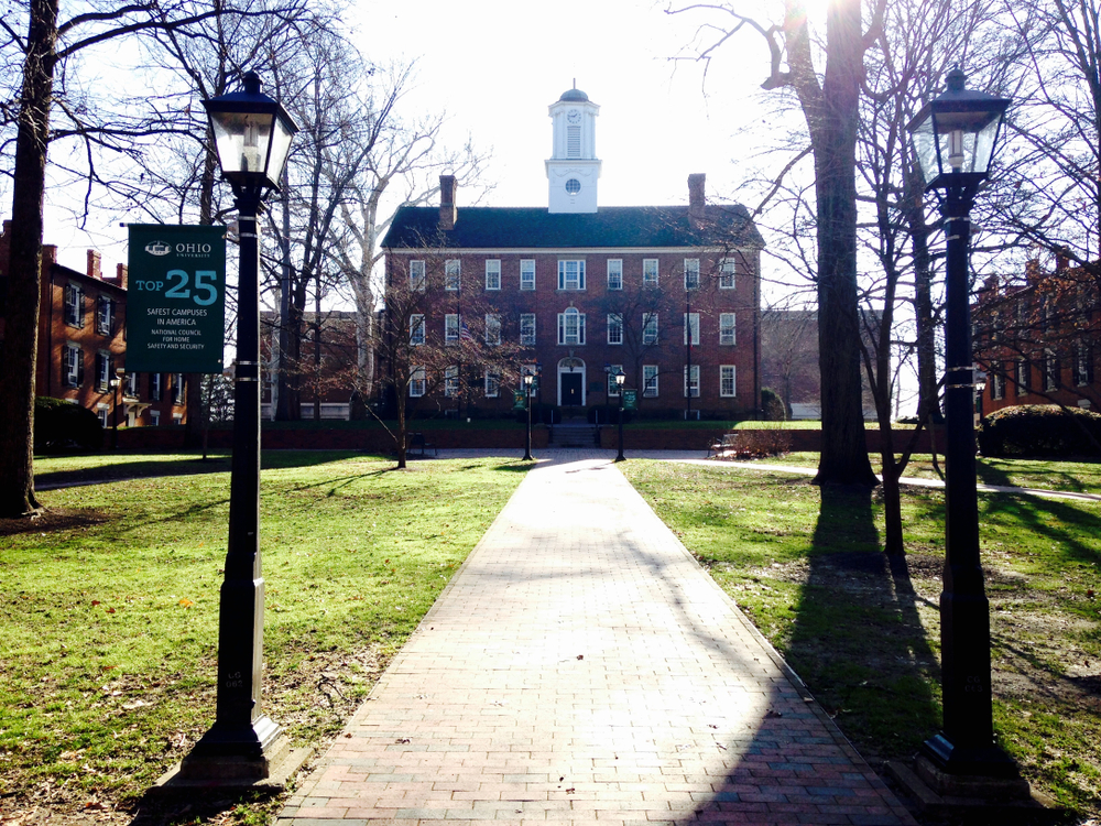 Red brick building with white steeple and vintage lamp post and brick walkway in foreground.