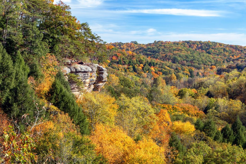 A view of autumn foliage and an overhanging outcrop a great place for Hiking in Hocking Hills