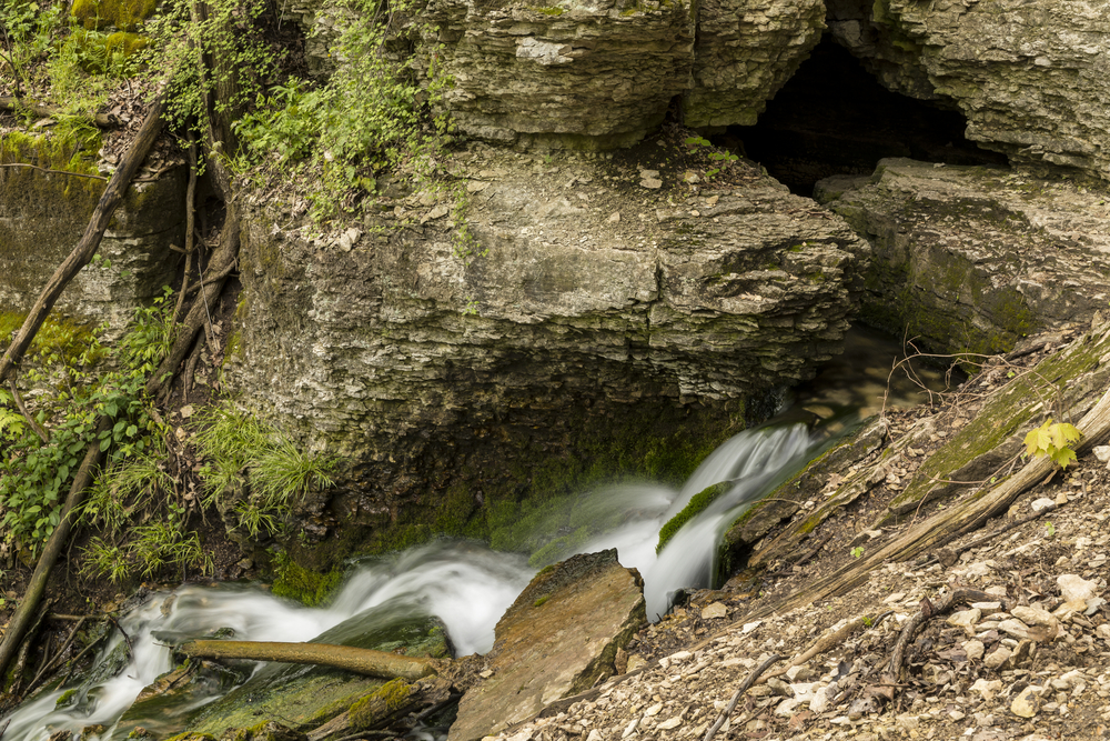 A skinny waterfall flowing over large rocks one of the best waterfalls in Iowa