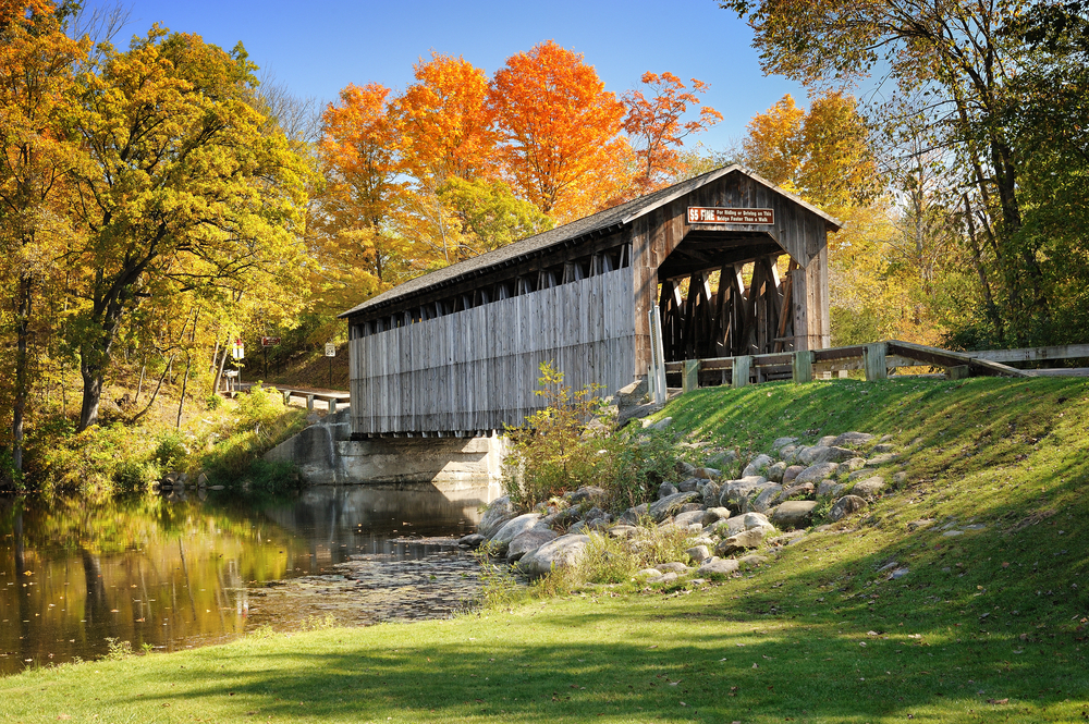 The wooden Fallasburg Covered Bridge in the fall on a sunny day in Michigan during Midwest road trips.