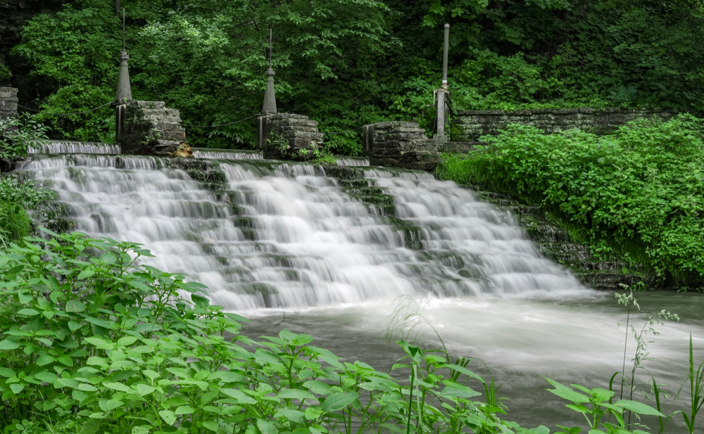 A large set of manmade rock steps that form a cascading waterfall surrounded by lush greenery in Iowa