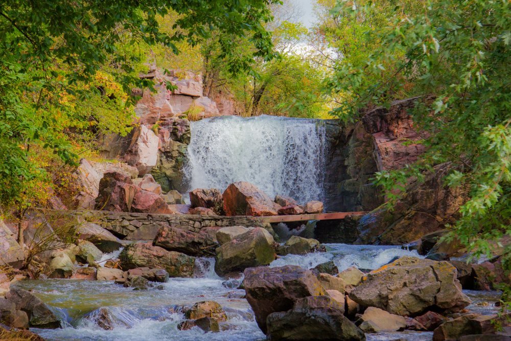 A large waterfall going down red rocks surrounded by green trees waterfalls in Minnesota