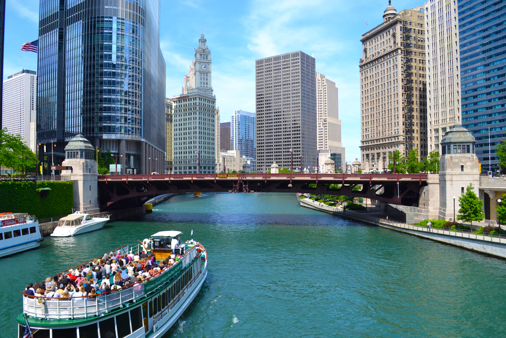 Large boat sailing the Chicago River with tourists on top observation deck.