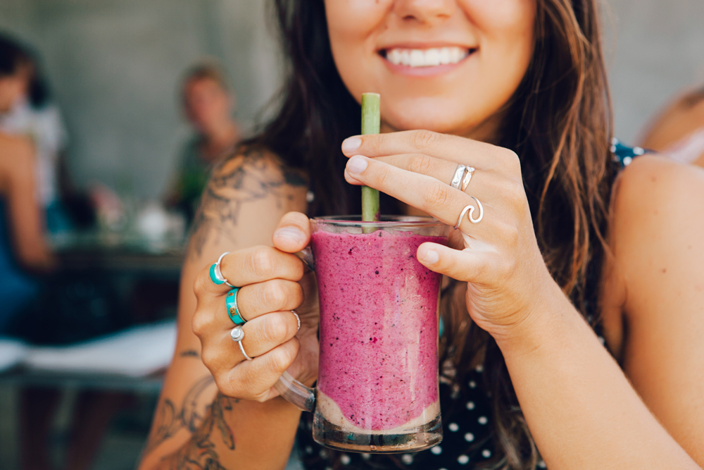 Women drinking a purple smoothie with a smile on her face
