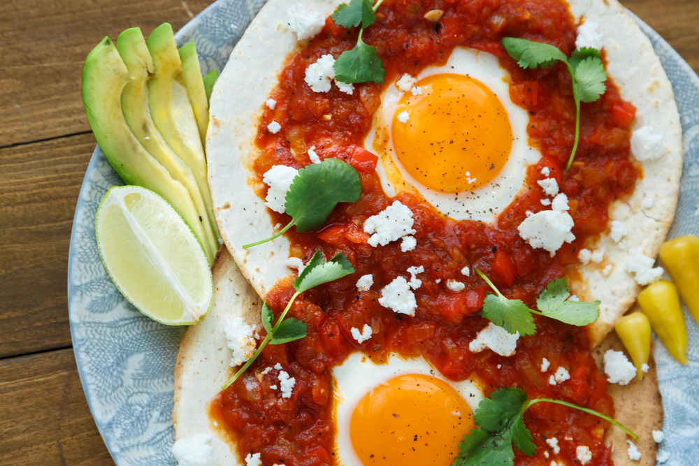 Huevos Rancheros on a plate with a side of avocado