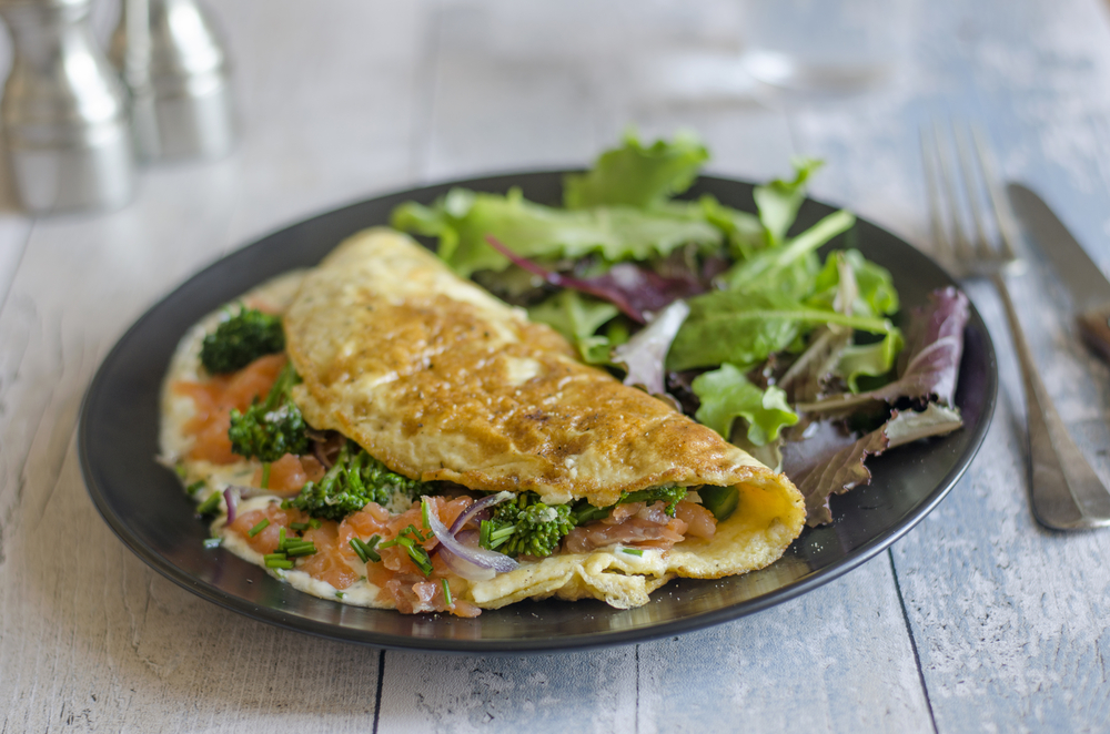 A plate containing salad and a salmon omelet