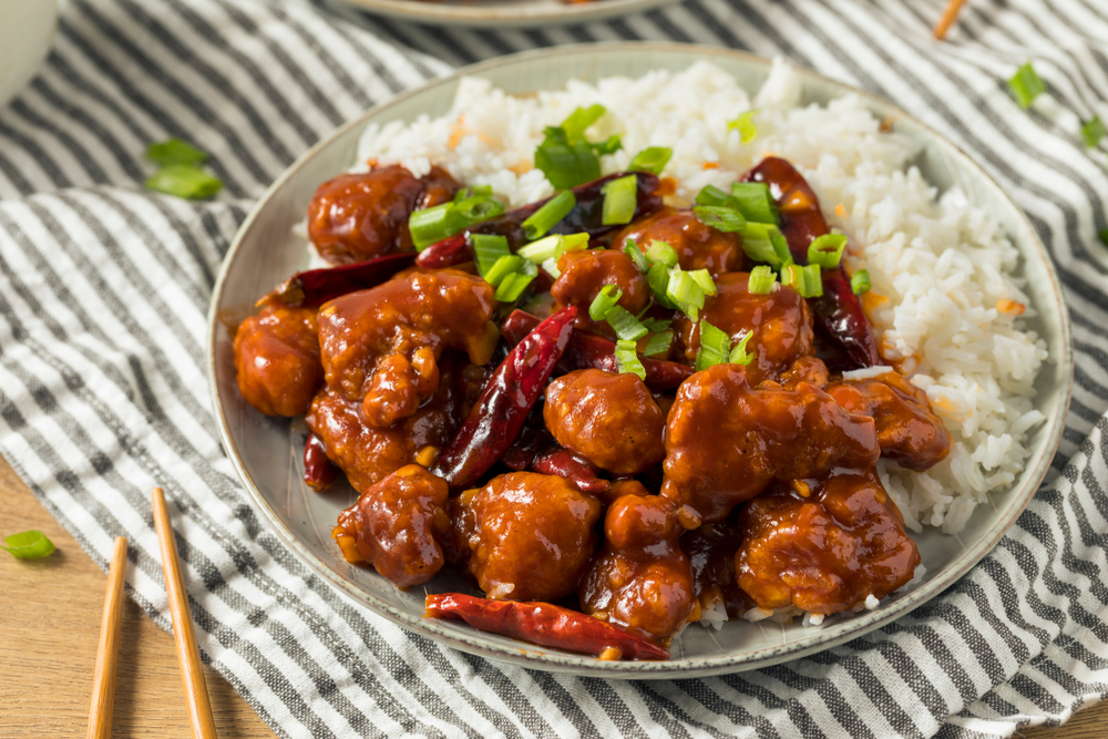 A plate of orange chicken with white rice at one of the best restaurants in Cincinnati.