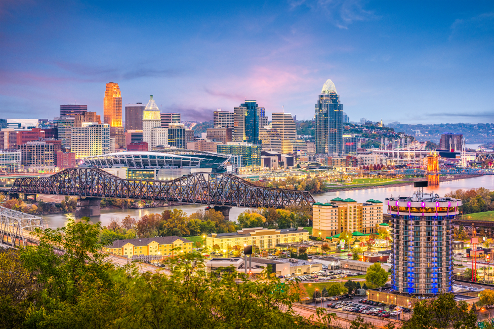 City with sky scrapers & river flowing through middle of it & large iron bridge over river. cities in the Midwest.