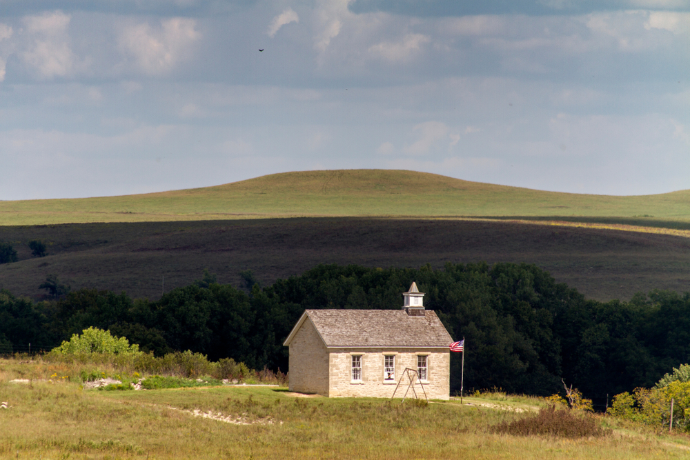 An old brick schoolhouse on the Tallgrass Prairie with hills in the background Things to do in Kansas