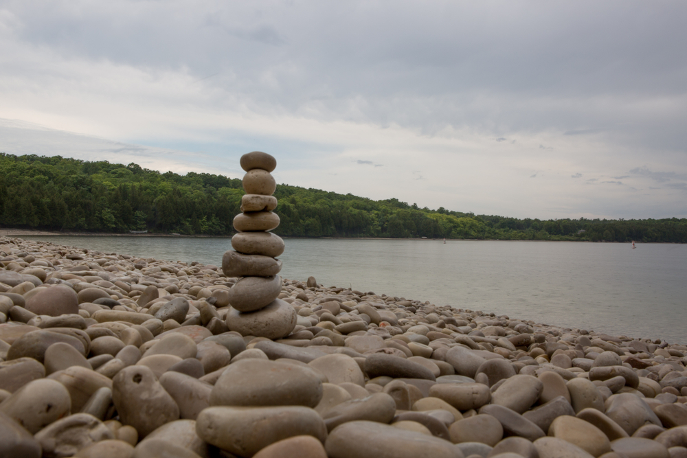 Pebbles piled up on a beach with trees in the background in an article about things to do in Door County