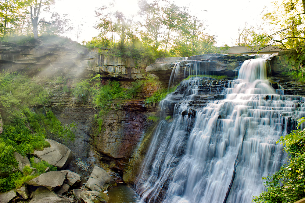 A large cascading waterfall surrounded by rocks. There is grass and moss growing on the rocks. Its one of the best things to do in Cuyahoga Valley National Park.