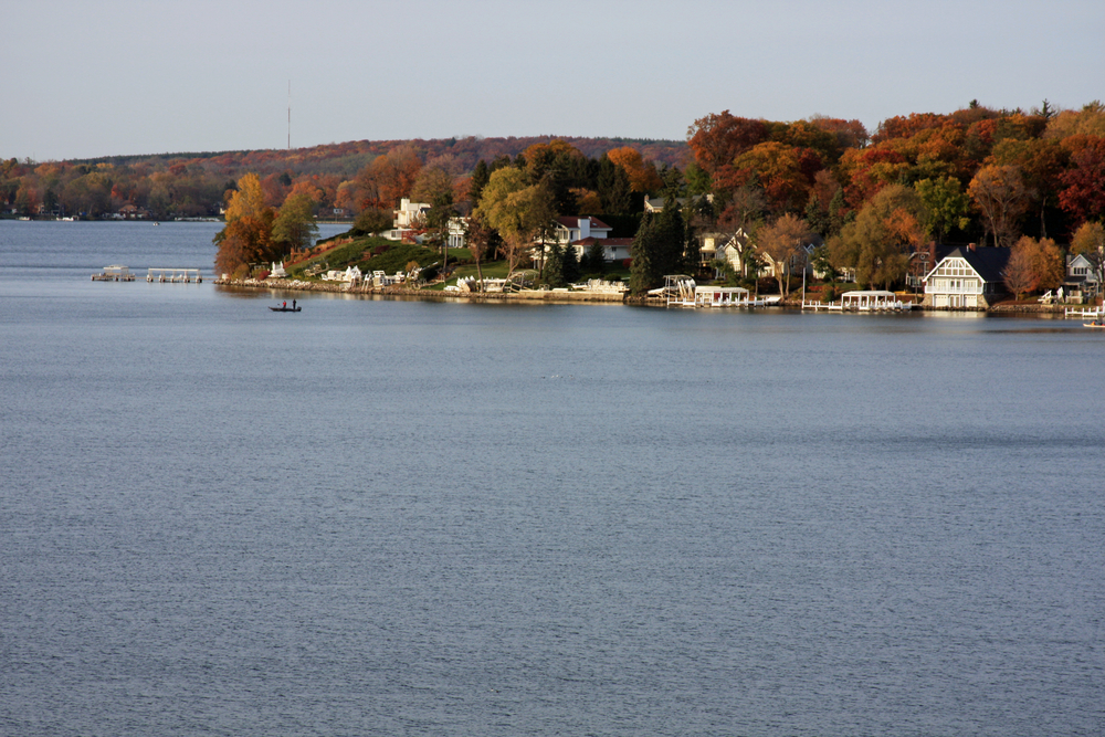 A Lake with white houses around and trees with fall colors a perfect place for Fall in Wisconsin