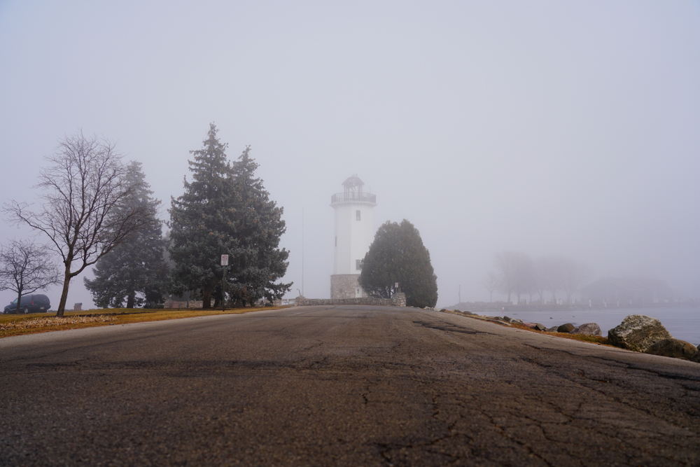 A lighthouse in the mist surrounded by trees in an article about fall in Wisconsin