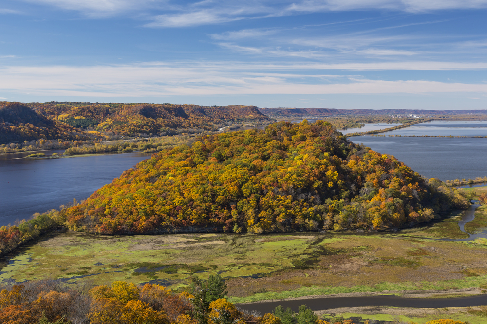 A hill in fall foliage with a lake beyond it