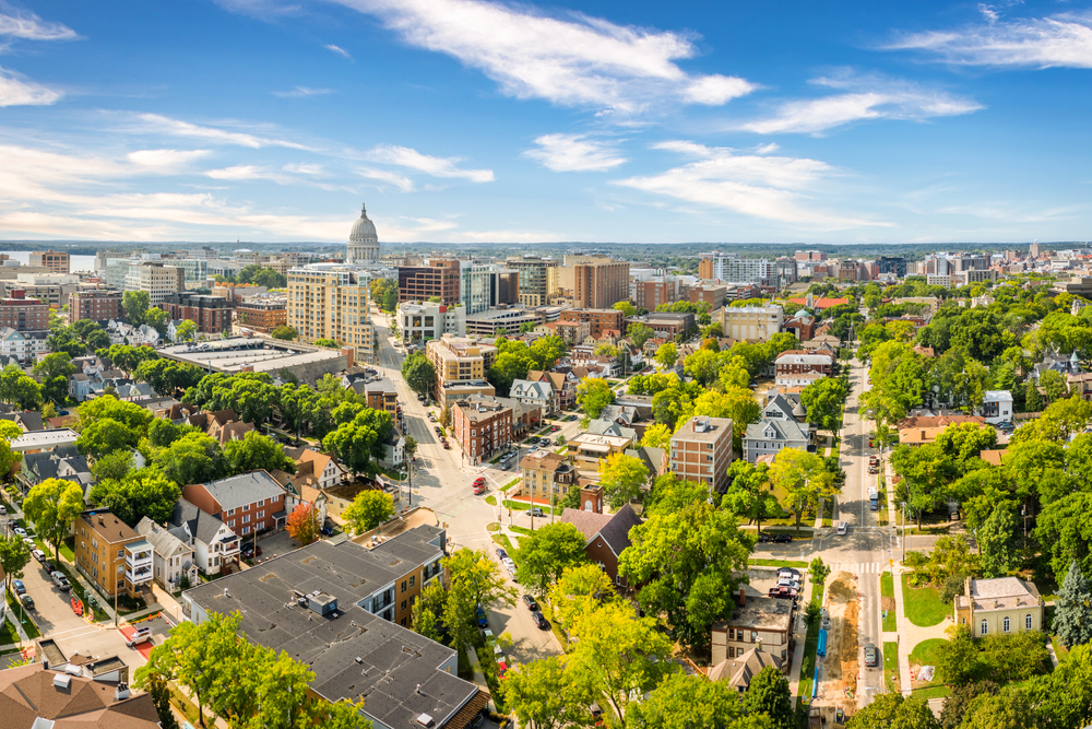 An aerial view of Madison Wisconsin on a sunny summer day. There are lots of buildings, both old and new, and trees covered in green leaves. One of the best places for Wisconsin weekend getaways 