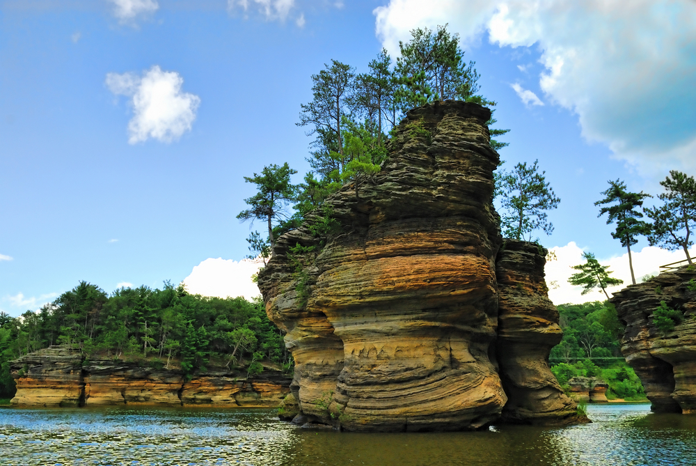 A unique rock formation in the Wisconsin Dells area in the water. The rocks are covered in trees.