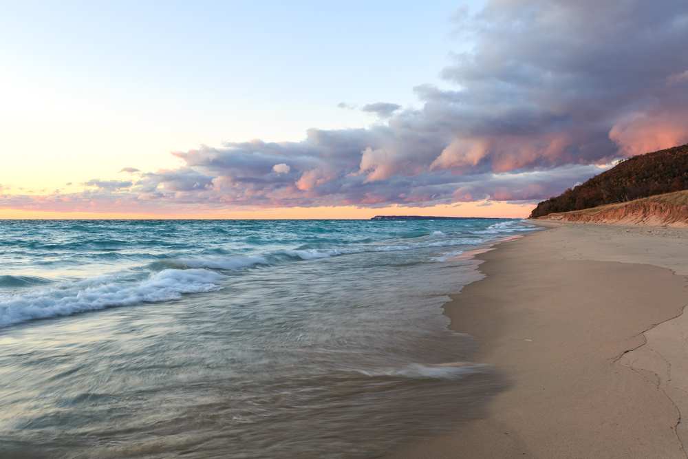 A beautiful beach with a sand dune in the distance at sunset. One of the best beaches in Traverse City