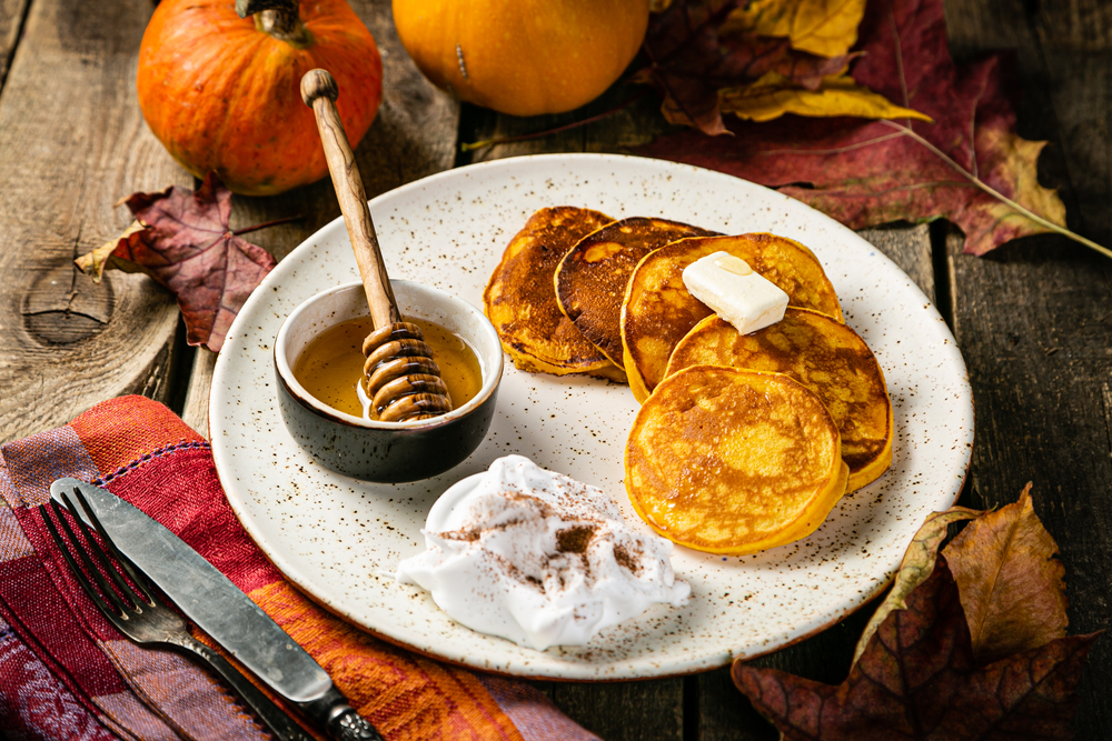 Pumpin pancakes on a plate with syrup and pumpkins