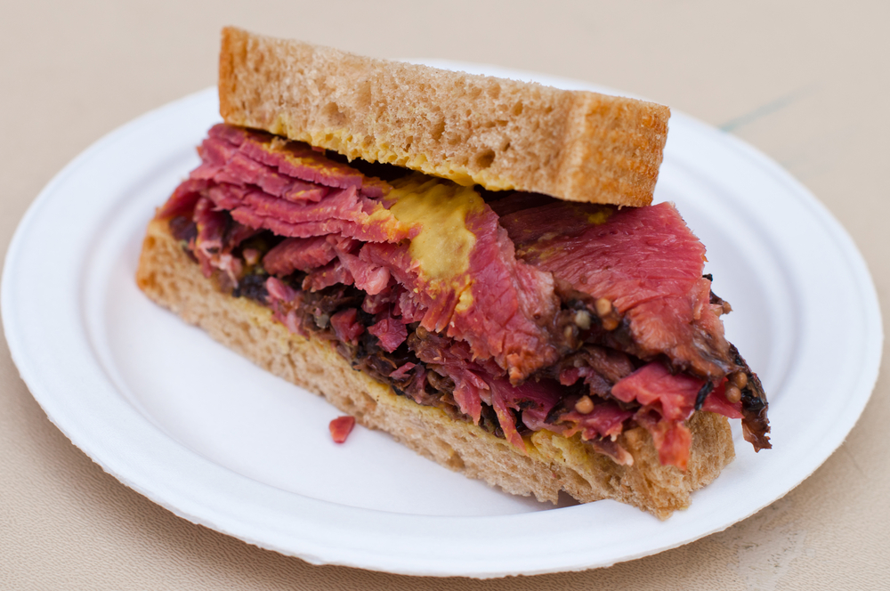 A Corn Beef with Beetroot Sandwich on a white plate