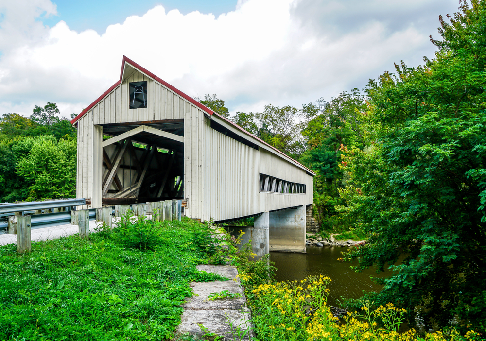 A white bridge with a red roof surrounded by foliage