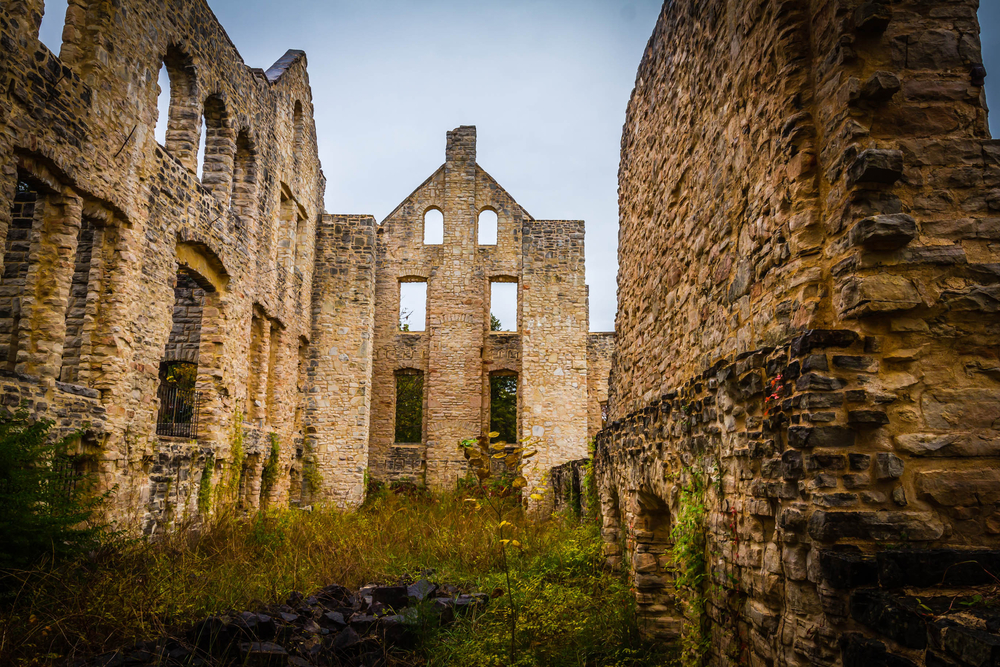 The inside of the Ha Ha Tonka Castle ruins. The ruins are made of a tan stone and there is grass growing on the ground. There is moss and dirt on the stone. It is a unique stop on Missouri road trips