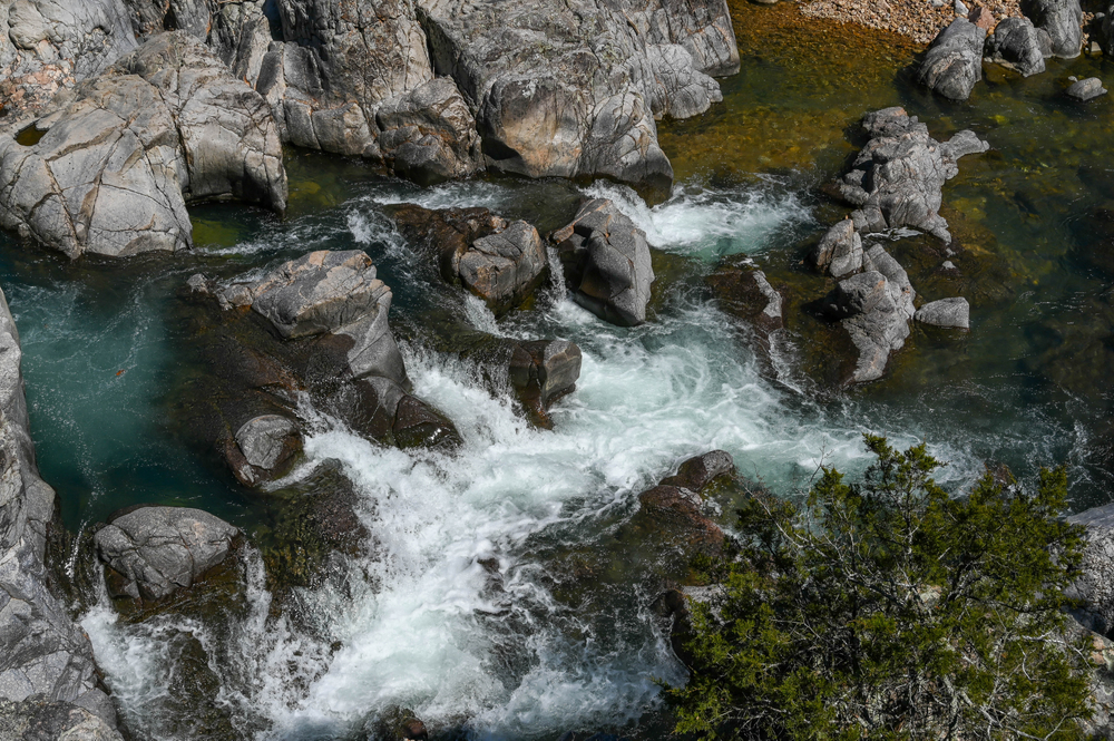 An aerial view of the Johnson Shut-ins a set of rocky waterfalls that create a pool of water. The rocks are grey and the water is fairly clear. It is one of the best Missouri road trips stops.